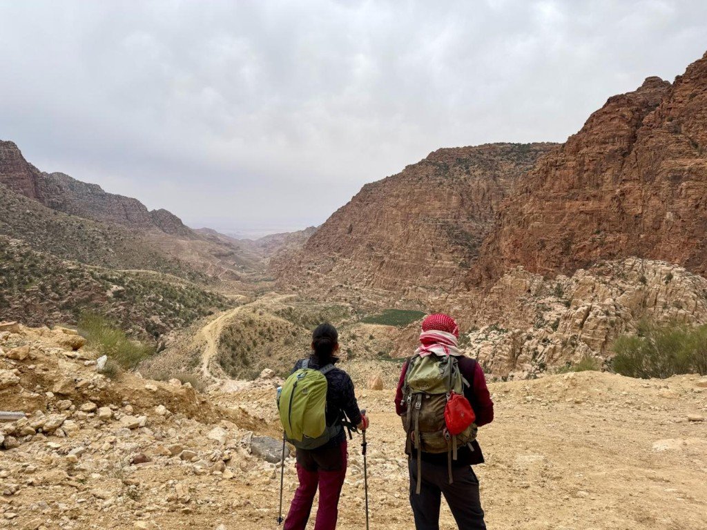 Two hikers overlooking a vast desert mountain valley