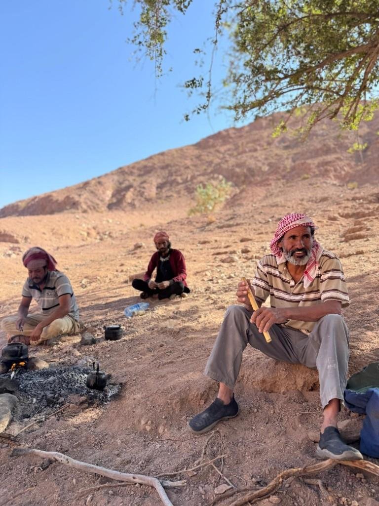 Local guides resting with a flute and tea over a desert campfire
