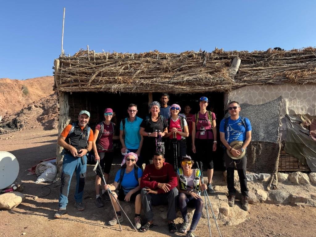 Hiking group posing outside a traditional desert shelter