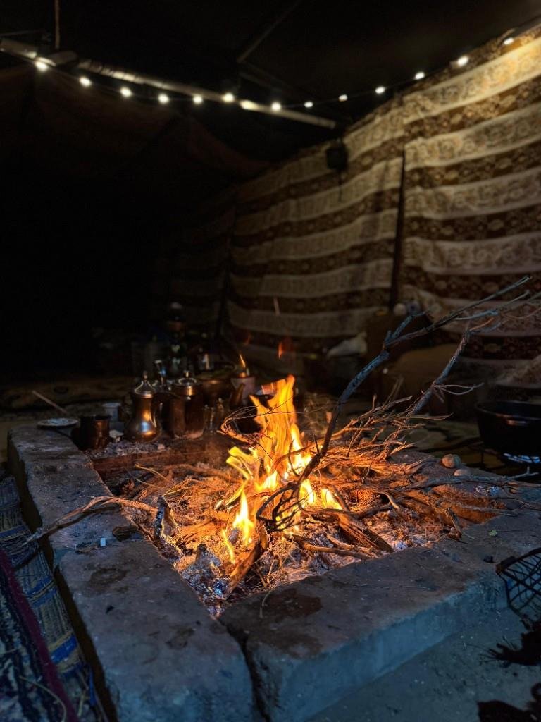 Campfire burning in a stone pit inside a traditional Bedouin tent