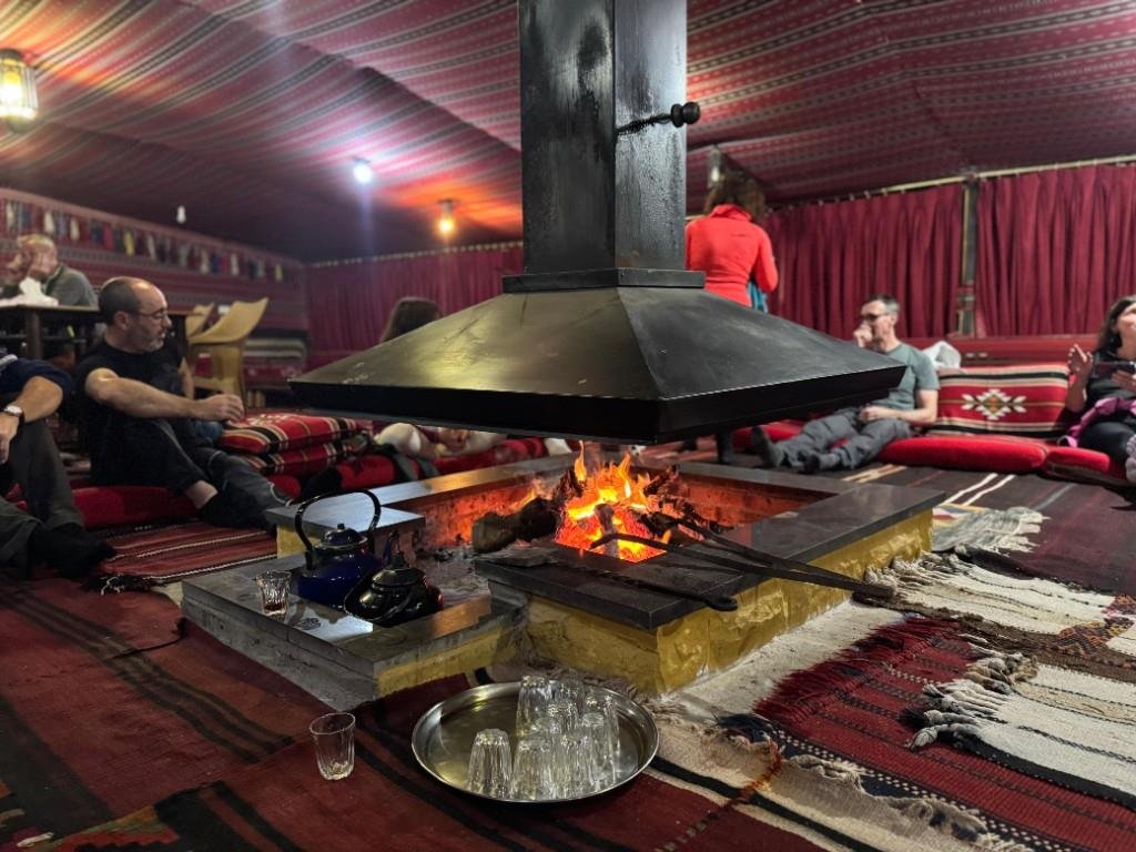 Guests relaxing around a fire pit inside a Bedouin tent
