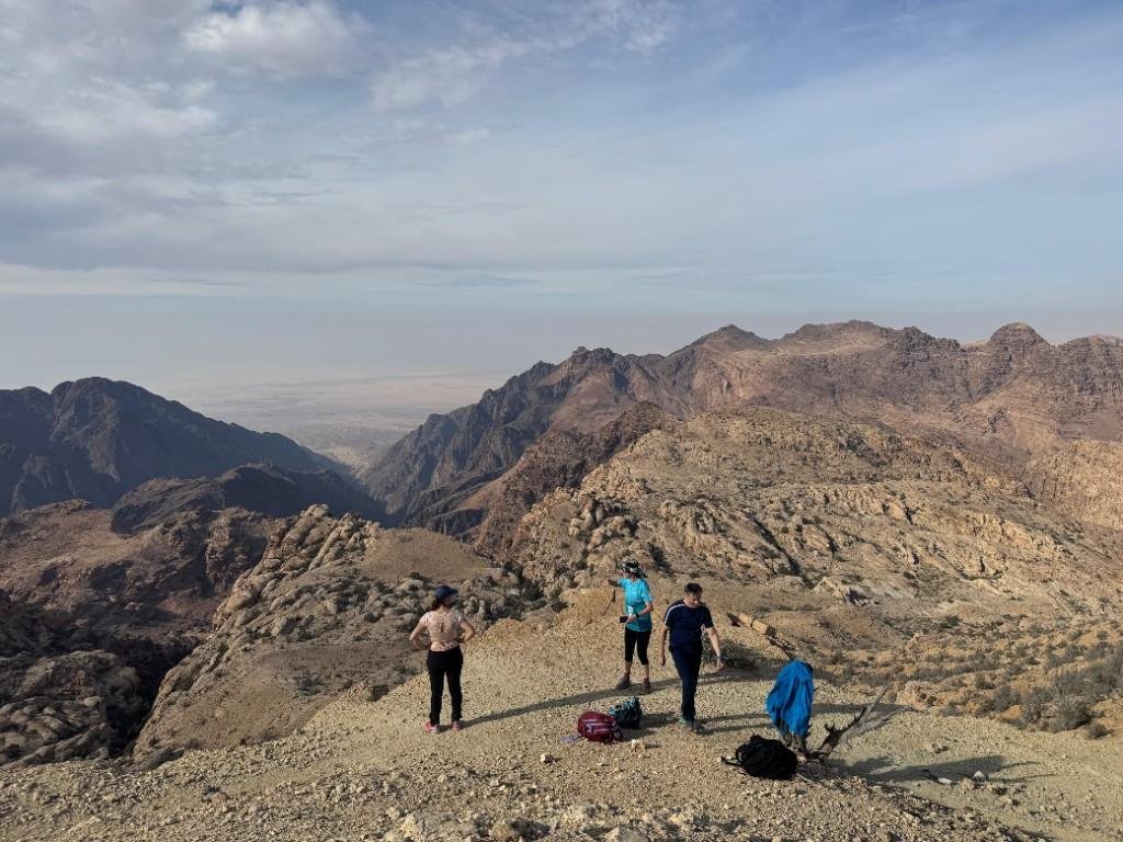 Hikers resting on a ridge overlooking a desert mountain valley